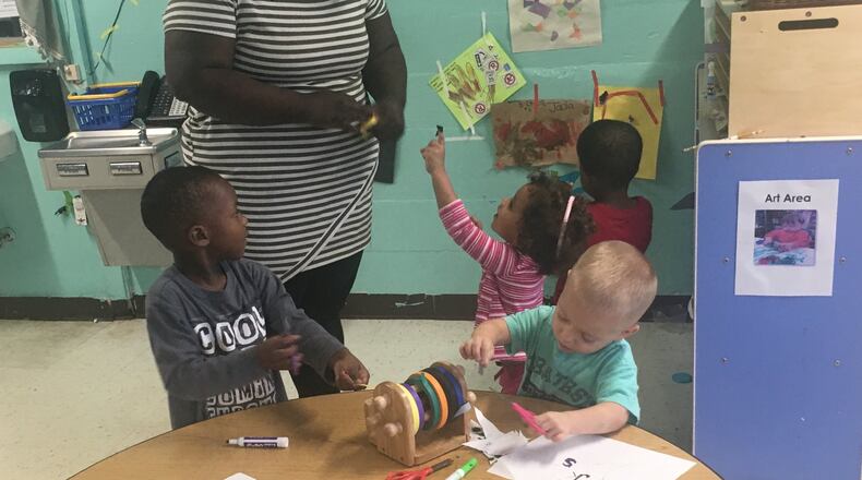 Chanie Corbitt, a preschool teacher at Dayton Christian Center on West Riverview Avenue, helps students with academic and fine-motor skill activities Oct. 21, 2016. The students wrote letters and numbers with the help of stencils, then used scissors to cut colored tape so they could hang up their papers. JEREMY P. KELLEY / STAFF