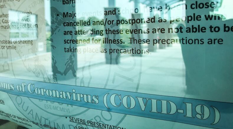 Belmont High School still has a faded COVID-19 sign on the front door of the school Thursday July 9, 2020. Guidelines for bus seating, face mask policies, alternative lunch rooms, and how long sick students must be fever free to return to school are among recommendations school officials are looking at. JIM NOELKER/STAFF