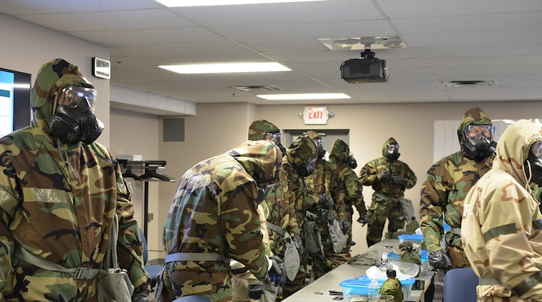 Airmen suit up in full mission oriented protective posture gear during a chemical warfare training class at the 88th Civil Engineer Squadron on Wright-Patterson Air Force Base. The gear protects from a toxic chemical, biological, radiological or nuclear environment. The course is a requirement for all personnel designated to deploy prior to departure. (U.S. Air Force photo)