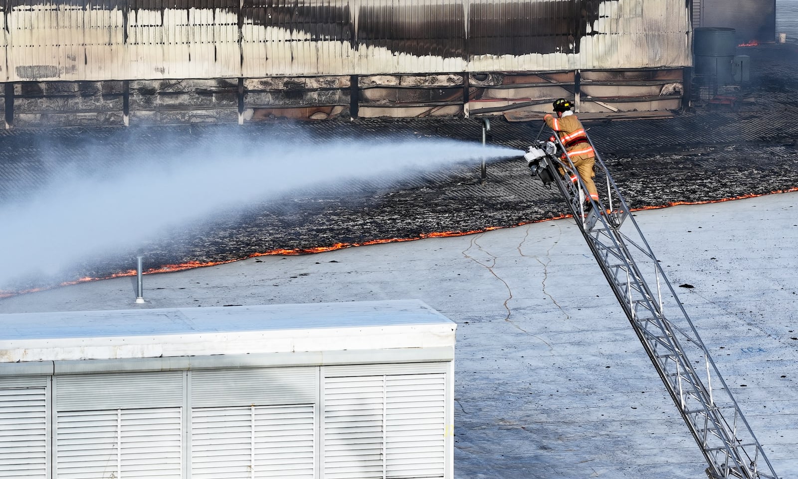 Morning crews work to extinguish remaining flames at the Fuyao Glass America plant in Moraine following a large fire. NICK GRAHAM / STAFF