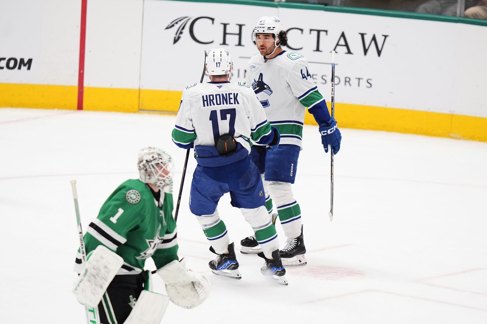 Vancouver Canucks' Filip Hronek and Kiefer Sherwood (44) celebrate after Sherwood scored against Dallas Stars' Casey DeSmith (1) in overtime of an NHL hockey game in Dallas, Tuesday, April 8, 2025. (AP Photo/LM Otero)
