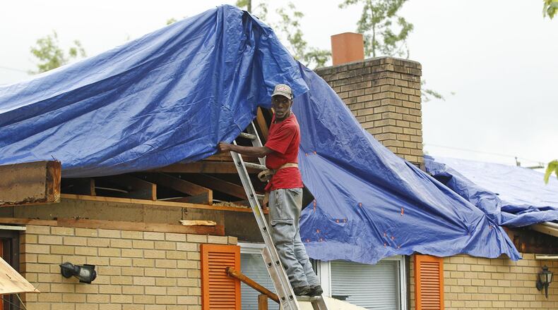 Contractors have been working to stabilize roofs and structures throughout tornado-damaged areas like this house on Denlinger Road in Trotwood. TY GREENLEES / STAFF