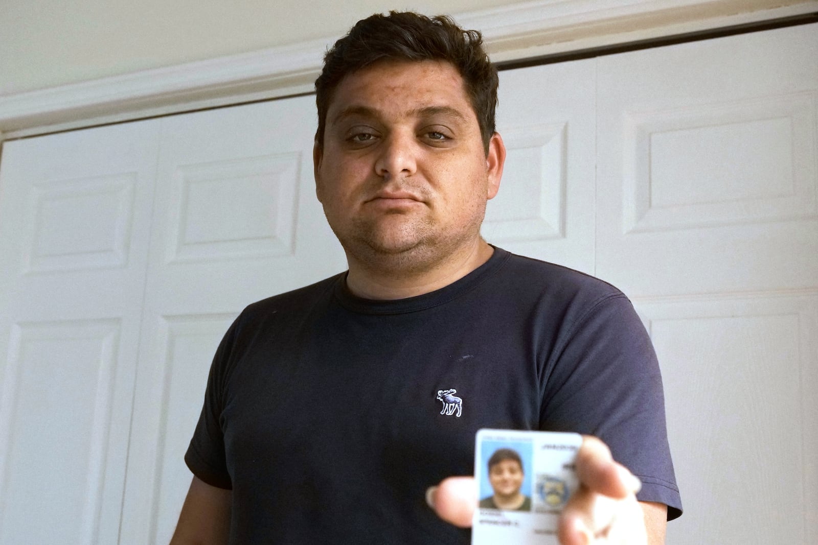 Spencer Goidel, an Equal Employment Opportunity Specialist with the Internal Revenue Service who was notified his job would be eliminated as part of the government's efficiency cuts, shows his government ID in Boca Raton, Fla., April 16, 2025. (AP Photo/Daniel Kozin)