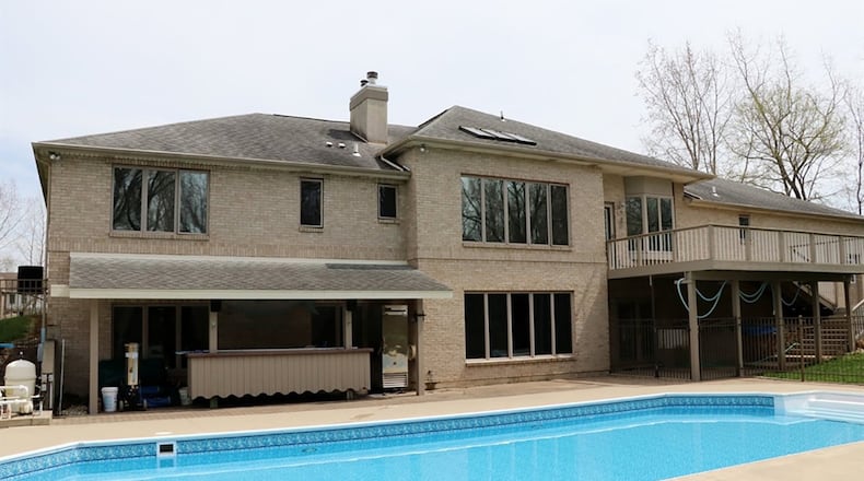 A multi-level wooden deck leads down to the fence-enclosed, in-ground swimming pool with outdoor bar area. The 6-acre property has 4 acres of woods, a private walking trail, and a metal pole bar with storage loft.
