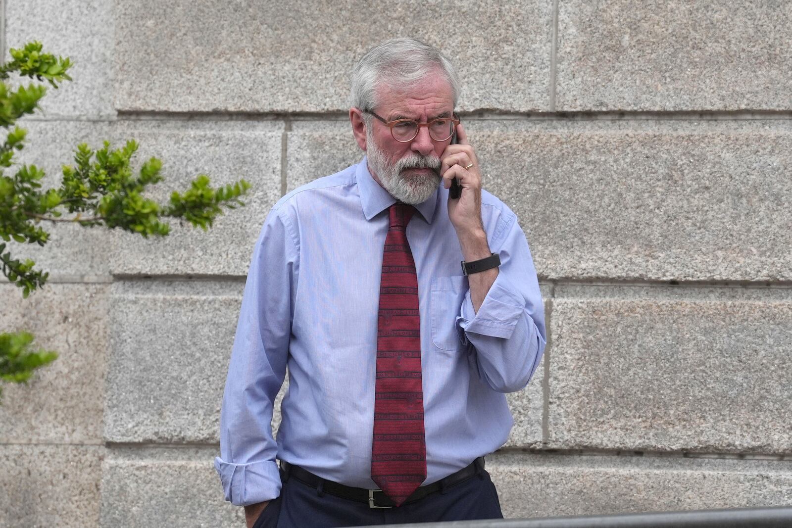 Former Sinn Fein president Gerry Adams on the phone outside the High Court in Dublin, Ireland, where he is bringing a legal action against the BBC over allegations about the murder of an MI5 spy, Thursday May 29, 2025. (Brian Lawless/PA via AP)