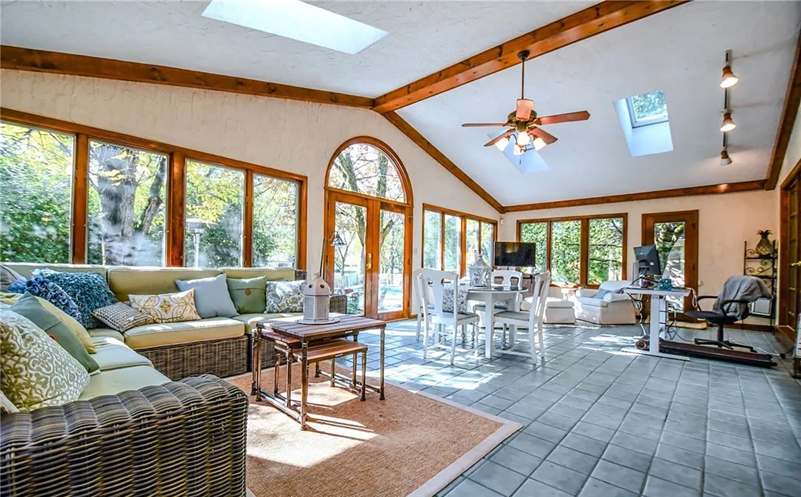 The sunroom has tile flooring, a vaulted ceiling with a wood beam, ceiling fan, skylights and track lighting. It opens to the back patio and pool area. CONTRIBUTED