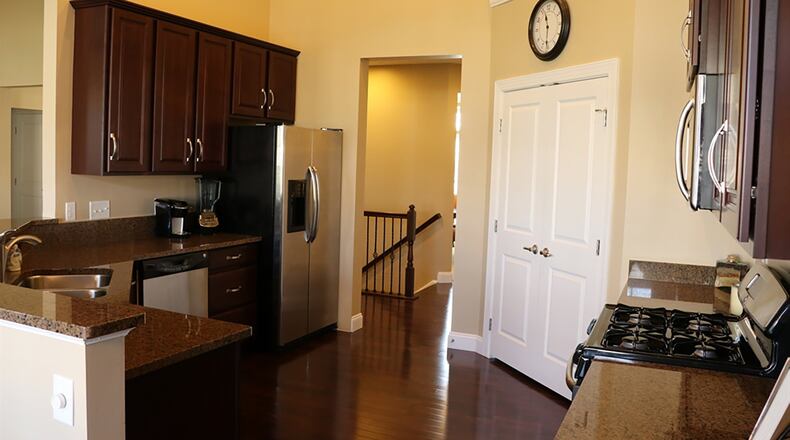 Cabinets and granite countertops fill two walls of the kitchen and surround stainless-steel appliances, including a gas range, dishwasher and a microwave.