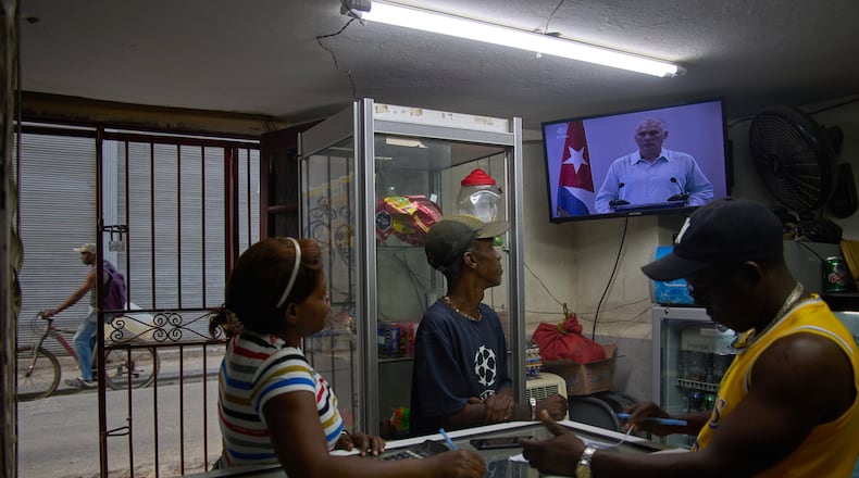 People inside a private convenience store see Cuban President Miguel Diaz-Canel speaking on TV in Havana, Cuba, Friday, March 13, 2026. (AP Photo/Ramon Espinosa)
