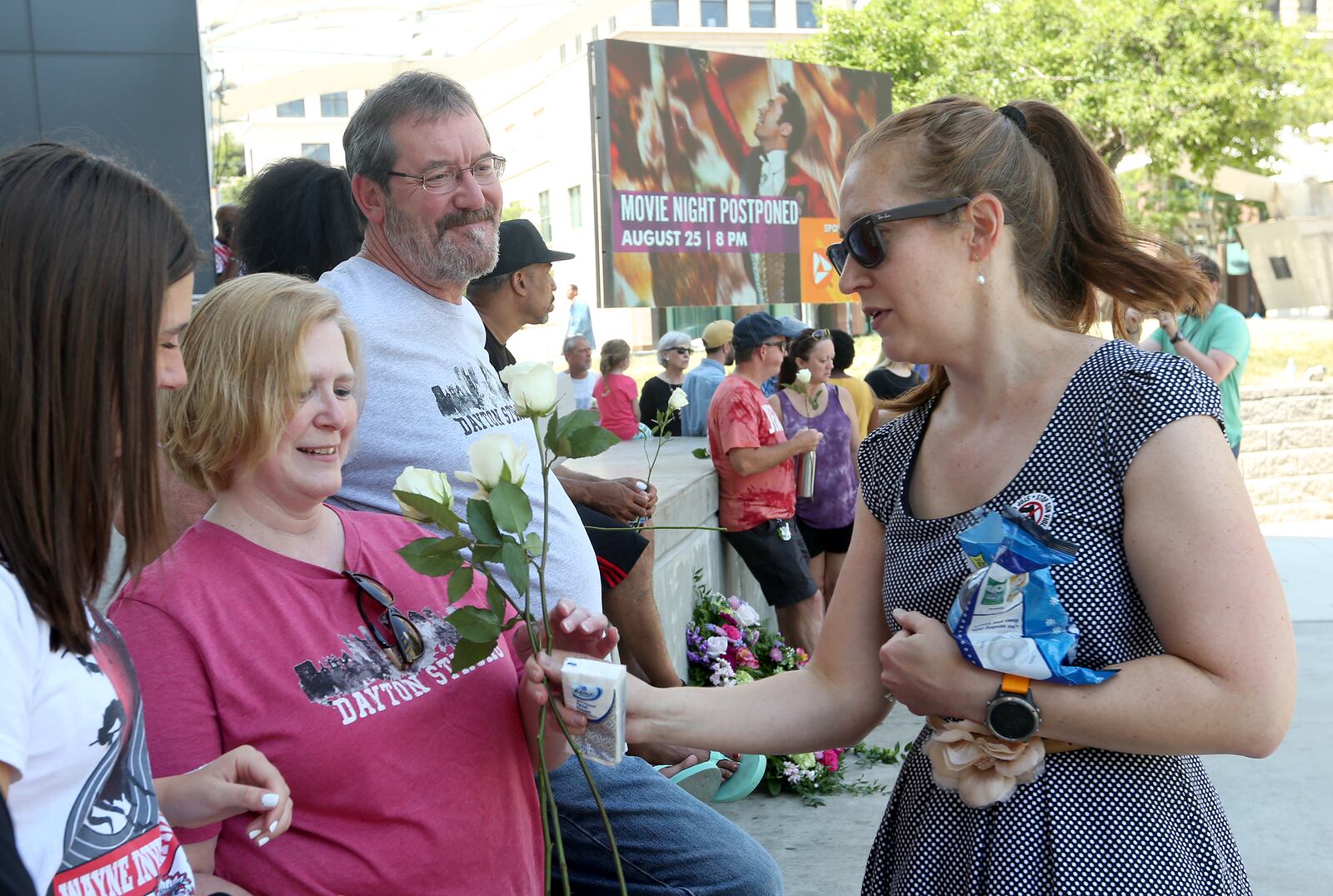 Lindsey Posey and her husband Terry handed out white roses, tissues and  mints to people gathered for a vigil at the Levitt Pavilion Sunday. LISA POWELL / STAFF
