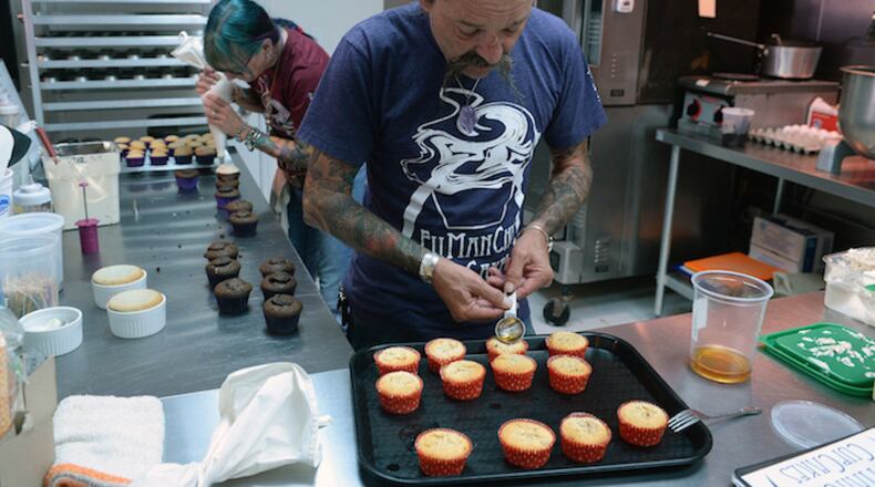 With his wife Beth taking care of his other cupcake creations, Andy carefully pours cinnamon whiskey into his his freshly baked "Flaming Peach" cupcakes. (T. Ortega Gaines/Charlotte Observer/TNS)