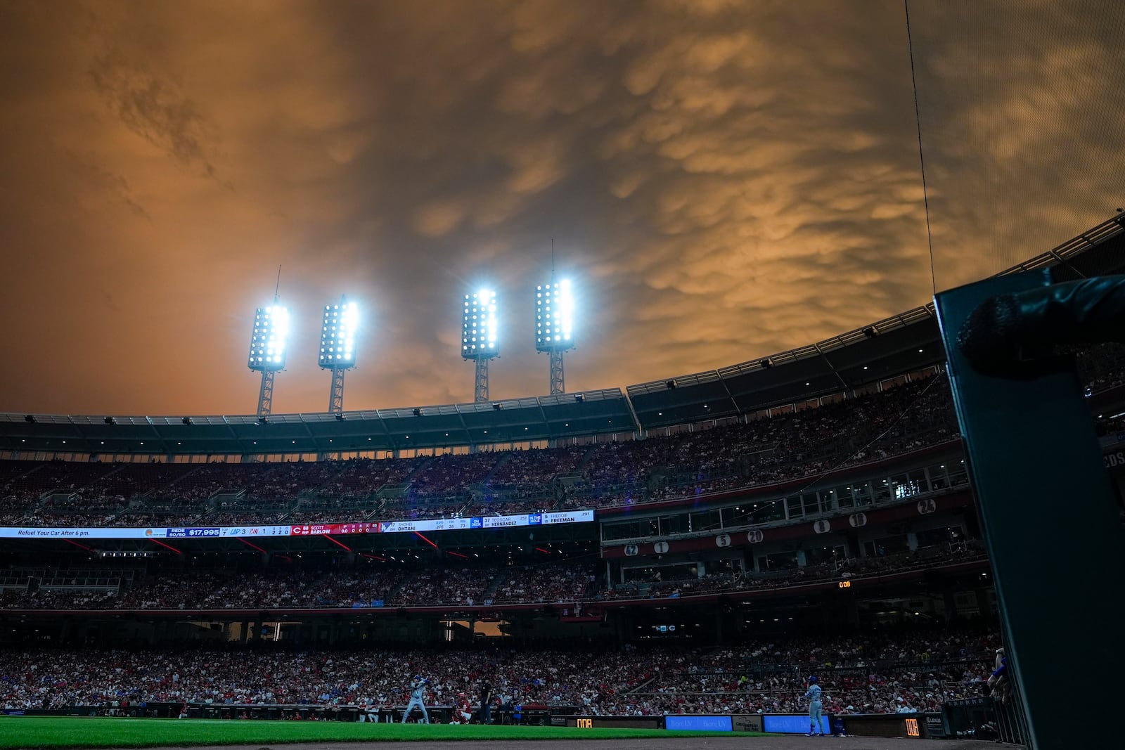 The sun sets as Los Angeles Dodgers' Shohei Ohtani is at bat during the seventh inning of a baseball game against the Cincinnati Reds Monday, July 28, 2025, in Cincinnati. (AP Photo/Carolyn Kaster)