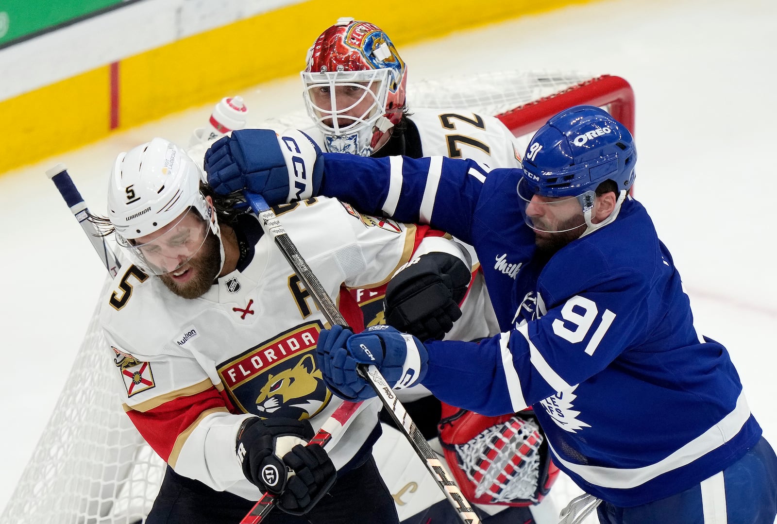 Toronto Maple Leafs' John Tavares (91) hits Florida Panthers' Aaron Ekblad (5) in front of teammate Sergei Bobrovsky (72) during third period NHL playoff hockey action in Toronto on Wednesday, May 14, 2025. Tavares received a roughing penalty on the play. (Frank Gunn/The Canadian Press via AP)