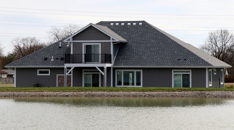 A composite deck with wrought-iron railing is accessible from the upstairs bedroom suite. A cathedral ceiling peaks over the great room with a wall of windows that looks out over the community park’s pond.