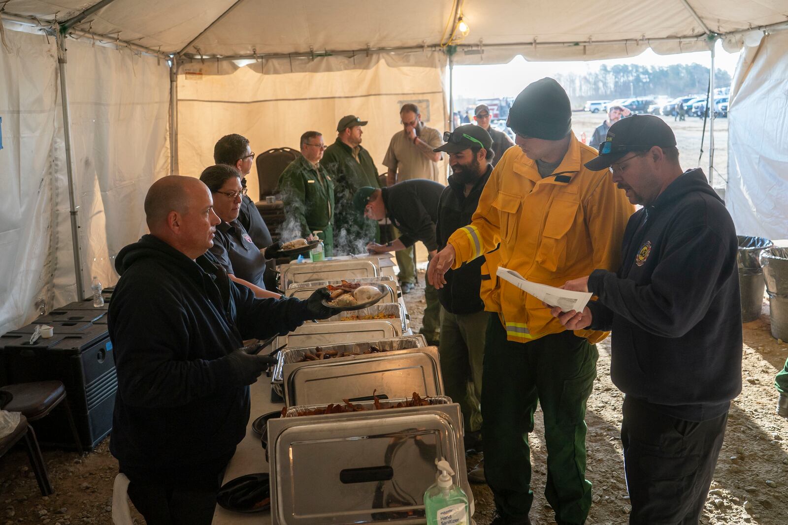 Firefighters from North Carolina and across the U.S. get breakfast after they gather for a morning coordination meeting Wednesday, March 26, 2025, in Mill Spring, N.C.. (AP Photo/Allison Joyce)