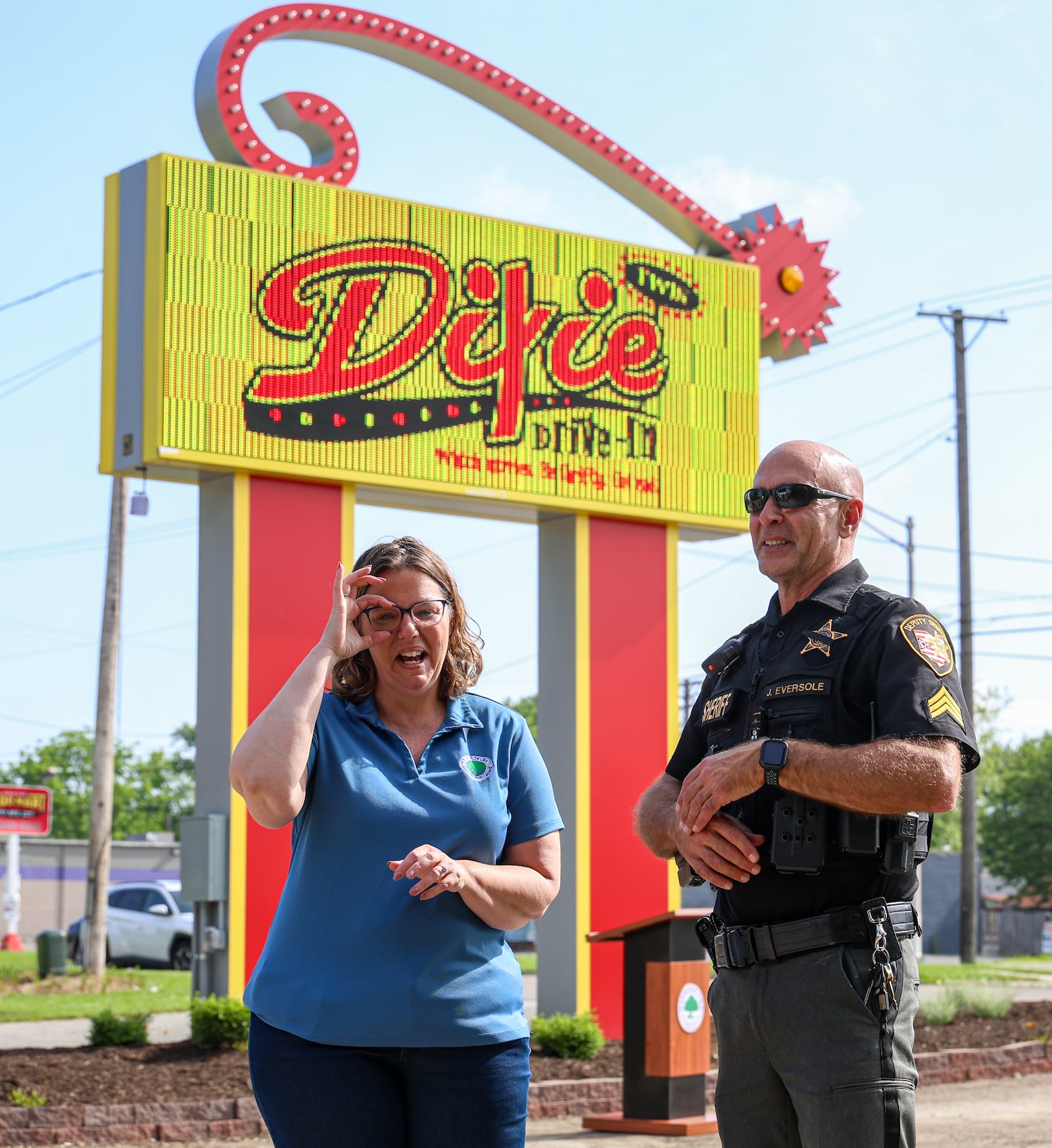 Harrison Township Administrator Shannon Meadows (left) talks with Montgomery County Sheriff Sgt. John Eversole during a ribbon cutting on Friday at Dixie Twin Drive-In. The nearly 70-year-old drive-in's original sign was damaged by remnants of Hurricane Helene last fall, and a new digital sign has recently been added to replace it. Aside from insurance money, township and county officials assited in getting funds through grants to help pay for the replacement.  BRYANT BILLING / STAFF