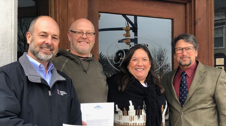 Miamisburg Community Foundation Vice President Shon Myers (left) and foundation President Greg Bell (right) present a check to A Taste of Wine owners Chris and Urmila Holloway Friday, Jan. 8, 2021. The check was one of three distributed to area eateries by the foundation's newly established Louis Epperson Restaurant Rescue Fund.