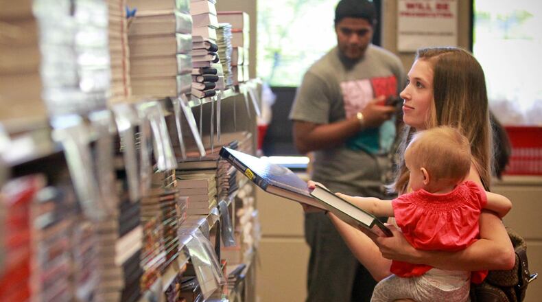 Second year Environmental Engineering student Melissa Lacaze shops for text books with her daughter Scarlett in the Sinclair College bookstore Wednesday. Ohio Democrats propose a “pay forward, pay back” system that would replace tuition for state schools. Students would pay a percent of their income after graduation for a certain number of years. This idea is already moving in Oregon and Washington. JIM WITMER / STAFF