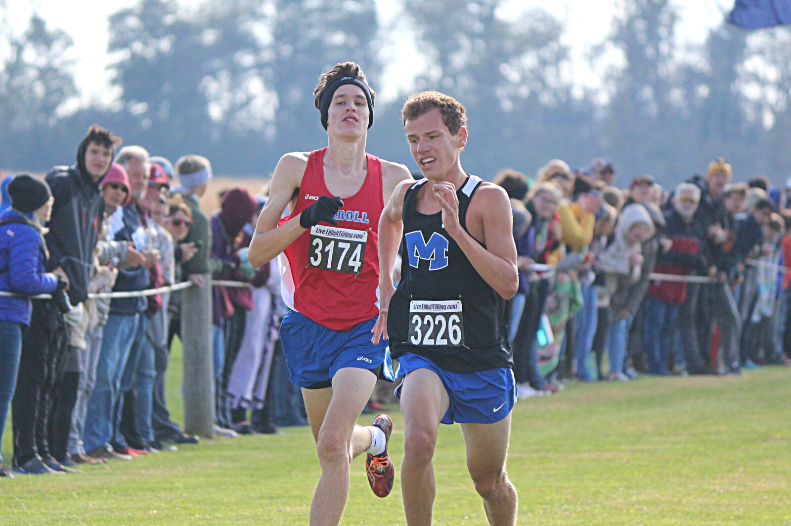 Miamisburg junior Corey Reese (3226) races Carroll’s Grant Arnold to the finish during the Division I district championships last Saturday in Cedarville. Reese finished eighth overall. Contributed / Greg Billing