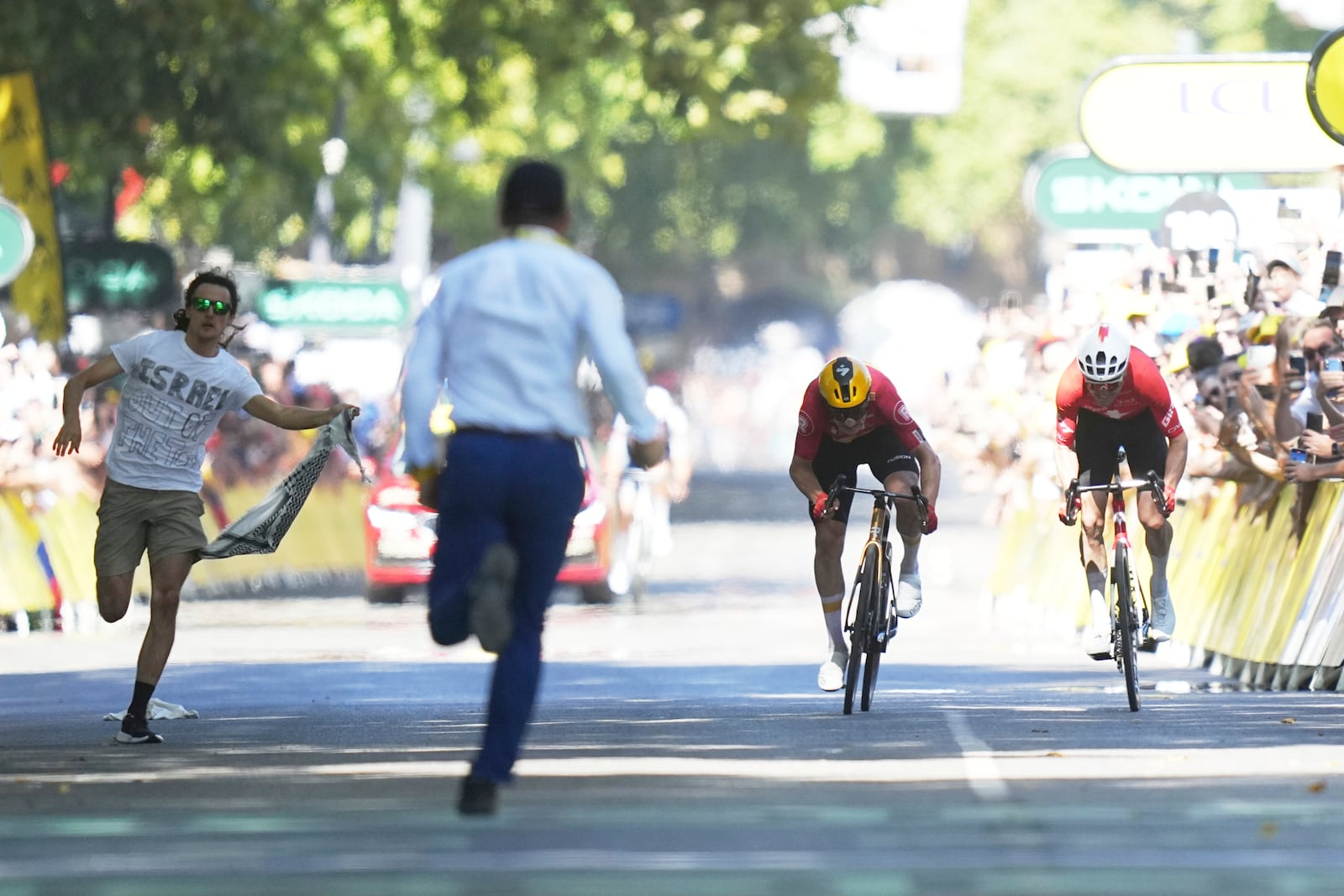 Norway's Jonas Abrahamsen, center right, and Switzerland's Mauro Schmid sprint as a protester tries to cross the finish line during the eleventh stage of the Tour de France cycling race over 156.8 kilometers (97.4 miles) with start and finish in Toulouse, France, Wednesday, July 16, 2025. (AP Photo/Thibault Camus)