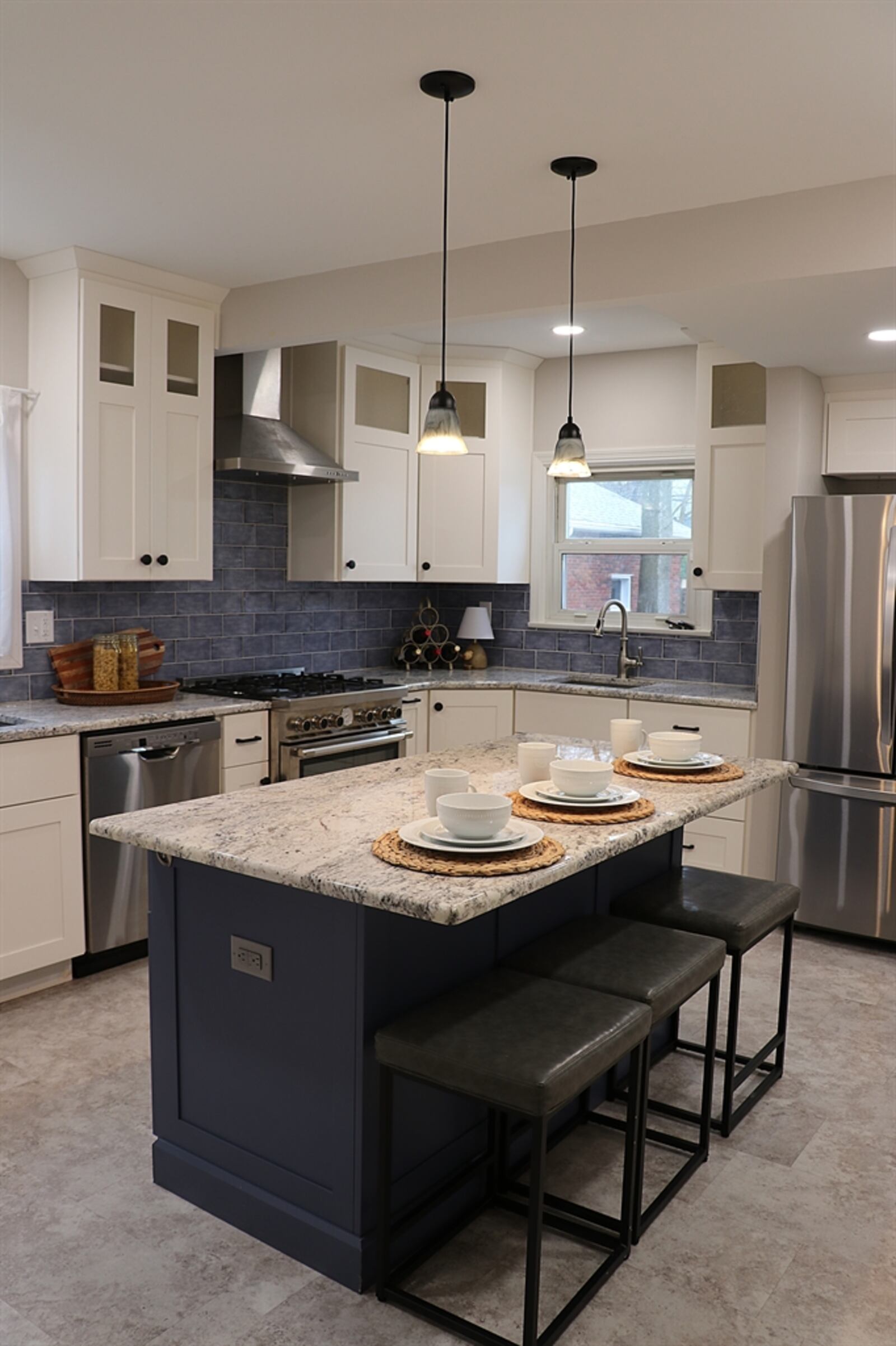 In the kitchen, frosted-glass panel doors accent the hanging cabinetry while the ceramic-tile backsplash gives a pop of color against the white cabinets.