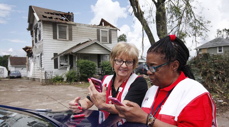 Red Cross volunteers Bonnie Russell, left, and Nadine Abdullah compare notes as the make damage assessments in Harrison Twp. after the Memorial Day tornadoes. TY GREENLEES / STAFF