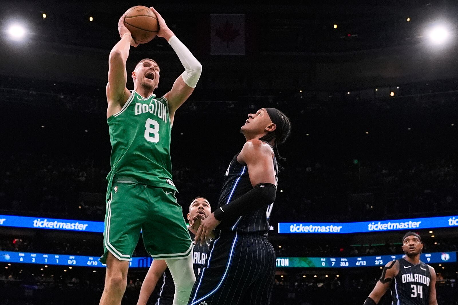 Boston Celtics center Kristaps Porzingis (8) grabs a rebound against Orlando Magic forward Paolo Banchero, right, during the first half in game 2 of a first-round NBA playoff basketball series, Wednesday, April 23, 2025, in Boston. (AP Photo/Charles Krupa)