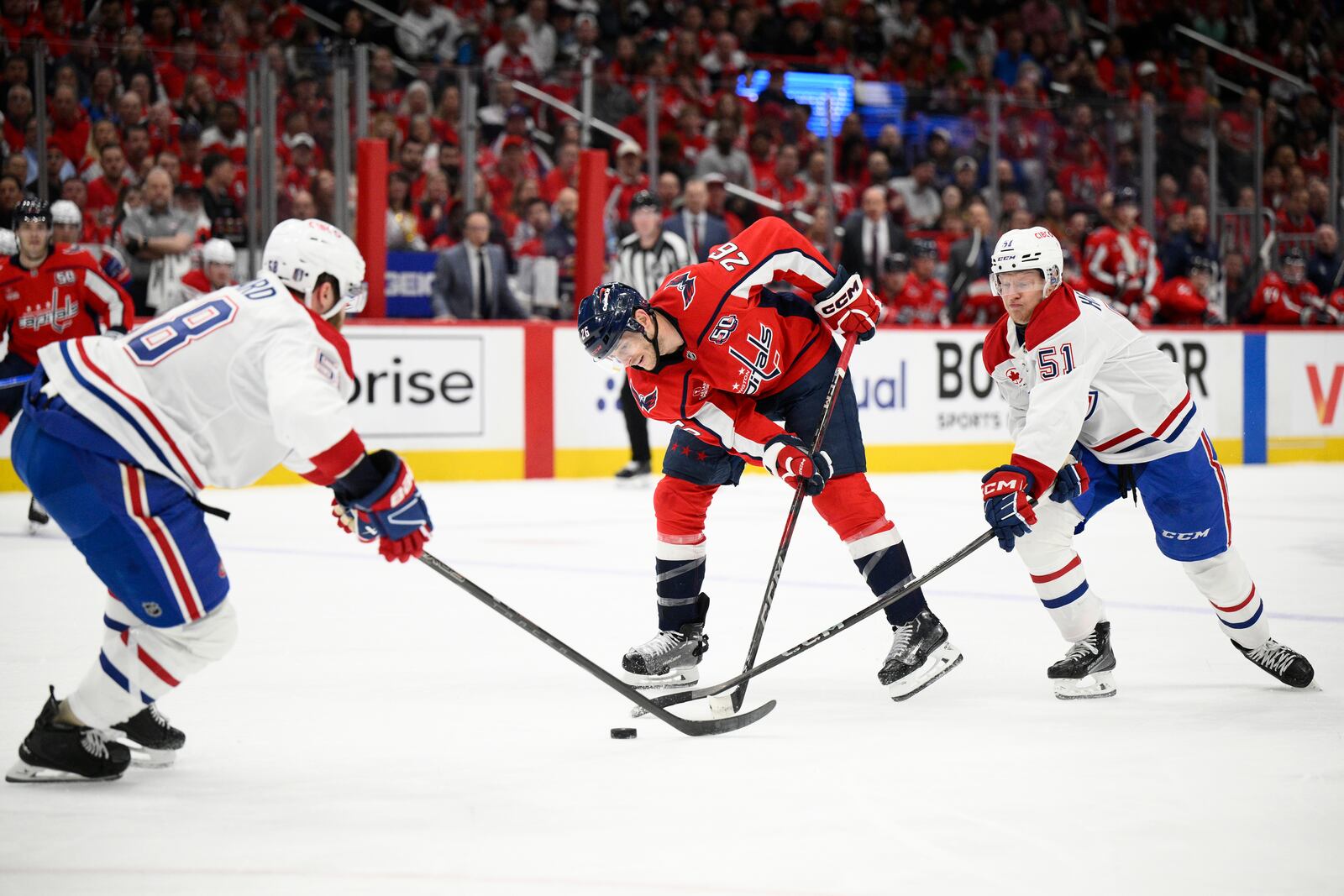 Washington Capitals center Nic Dowd (26) battles for the puck against Montreal Canadiens left wing Emil Heineman (51) and defenseman David Savard (58) in the first period of Game 2 of a first-round NHL hockey playoff series Wednesday, April 23, 2025, in Washington. (AP Photo/Nick Wass)