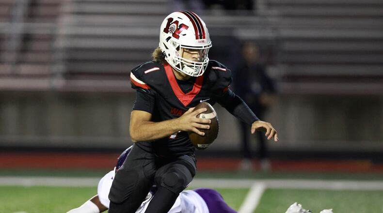 Wayne quarterback Tyrell Lewis avoids a tackle by Middletown's Jordan Vann as he rolls out during Friday's game. BILL LACKEY/STAFF
