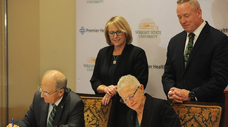Tom Gunlock, chair of the Wright State University Board of Trustees, and Kathleen Carlson, chair of the Premier Health Board of Trustees, signed an expanded affiliation agreement on Friday, Dec. 15, 2023. They were joined by (standing) Sue Edwards, president of Wright State University, and Michael C. Riordan, president and CEO of Premier Health. MARSHALL GORBY\STAFF
