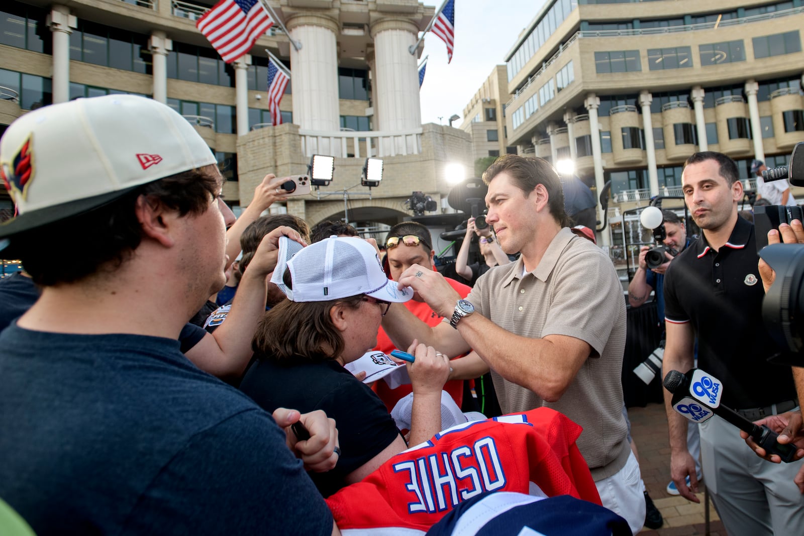 Washington Capitals forward T.J. Oshie, right, signs autographs for fans after announcing his retirement from the NHL at Washington Harbour, Monday, June 9, 2025, in Washington. (AP Photo/Rod Lamkey, Jr.)