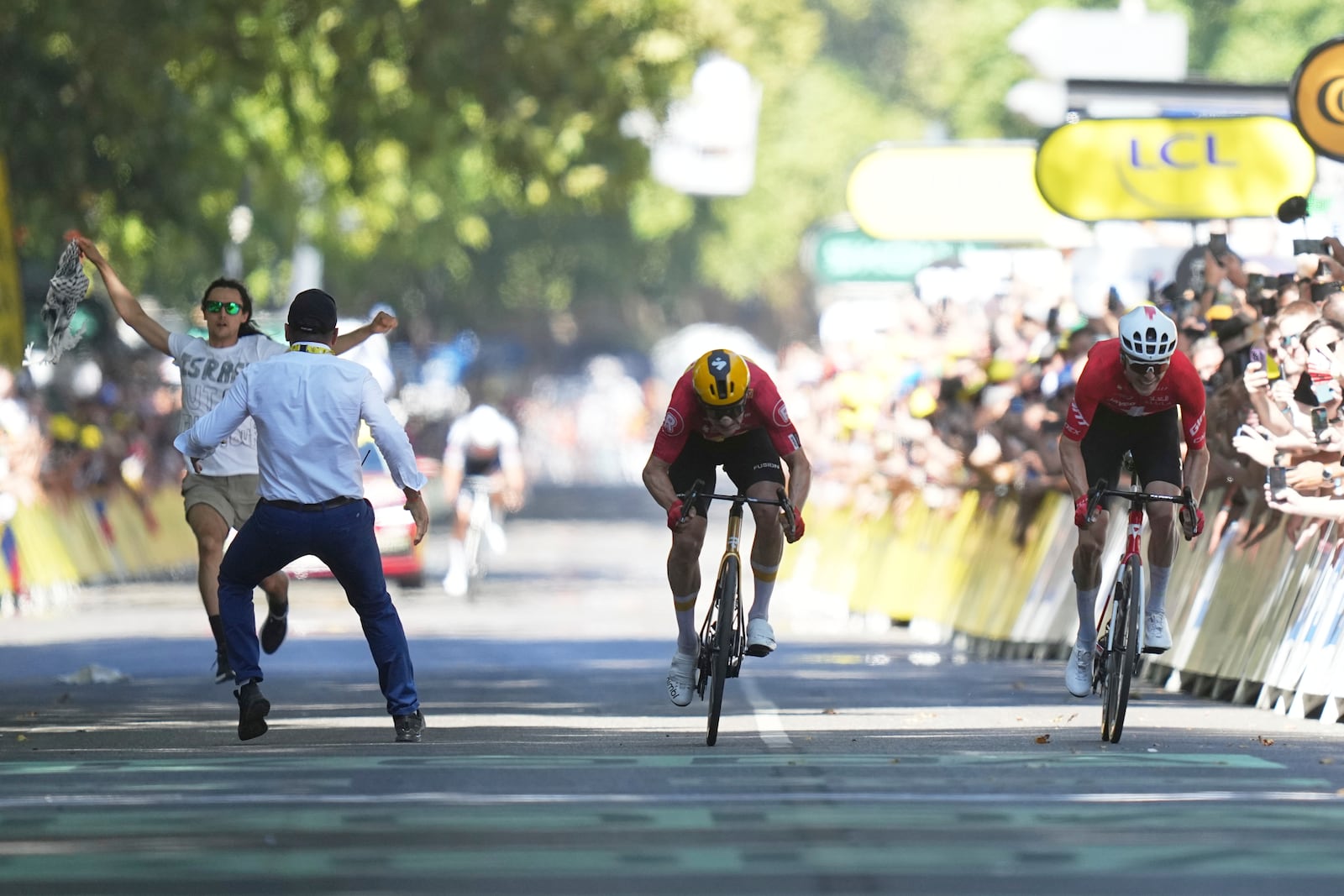 Norway's Jonas Abrahamsen, center, and Switzerland's Mauro Schmid sprint as a protester tries to cross the finish line during the eleventh stage of the Tour de France cycling race over 156.8 kilometers (97.4 miles) with start and finish in Toulouse, France, Wednesday, July 16, 2025. (AP Photo/Thibault Camus)