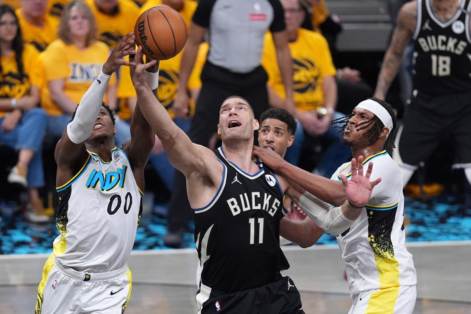 Milwaukee Bucks' Brook Lopez (11) reaches for a loose ball along with Indiana Pacers' Bennedict Mathurin (00) and Myles Turner, right, during the first half of a first-round NBA basketball playoff game, Saturday, April 19, 2025, in Indianapolis. (AP Photo/Michael Conroy)