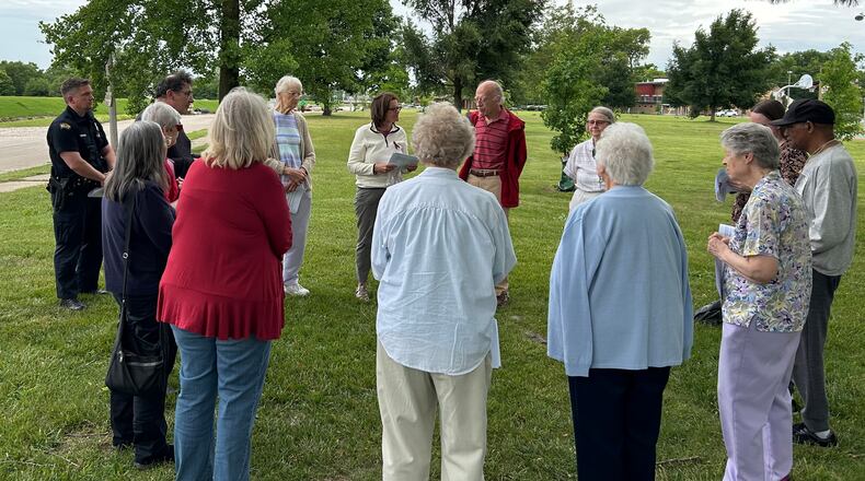 Two Dayton police officers join a group of Dayton-area residents holding a prayer vigil for homicide victims June 8, 2024, at McIntosh/Riverview Park in Dayton. JEREMY P. KELLEY / STAFF