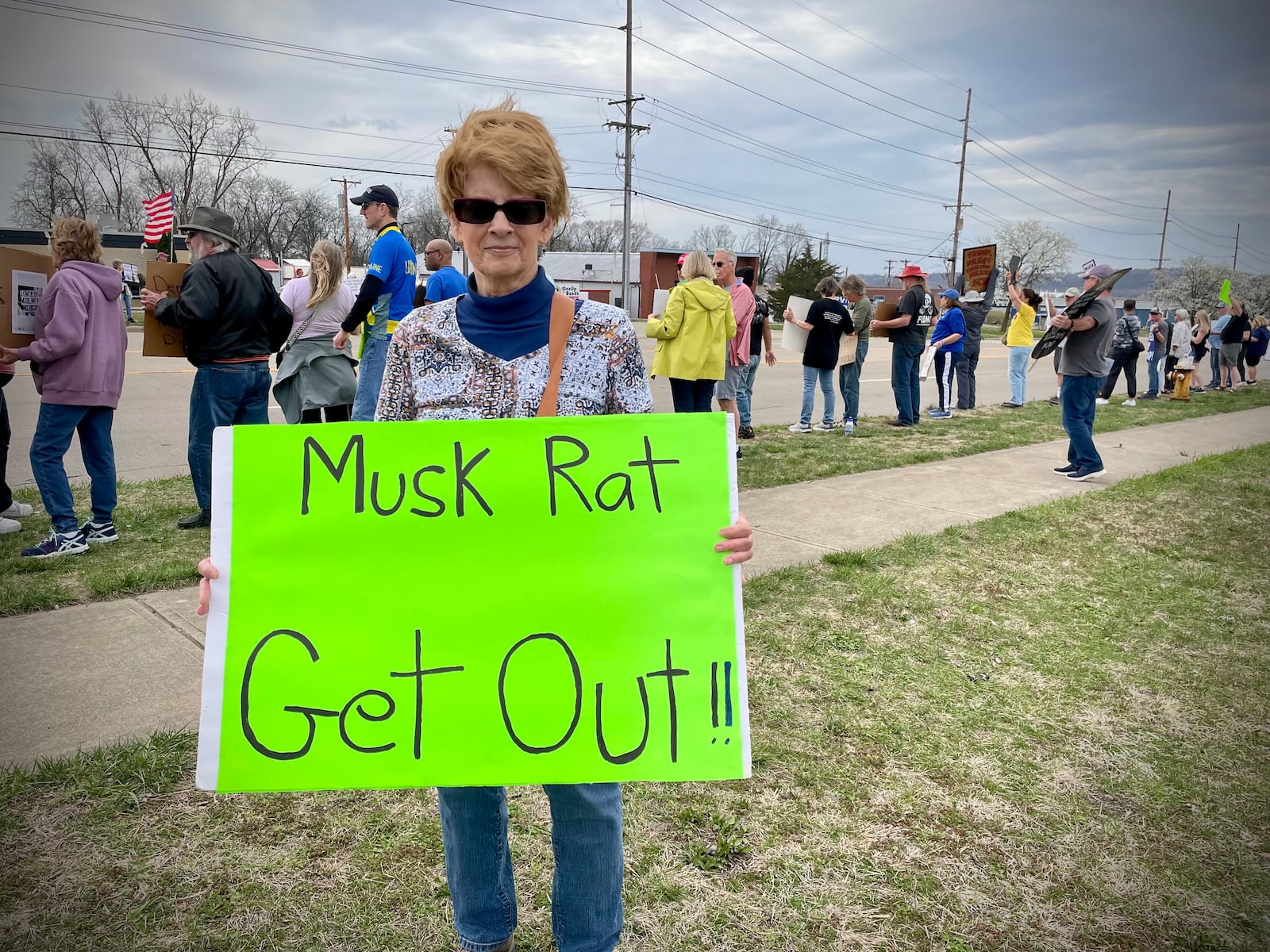 A crowd of more than 100 people lined both sides of West Dorothy Lane in front of the Tesla Service Center in Moraine on Saturday, March 29 as part of a nationwide “Tesla Takedown” movement. Pictured is organizer Kathy Jones of Dayton. NATALIE JONES/STAFF