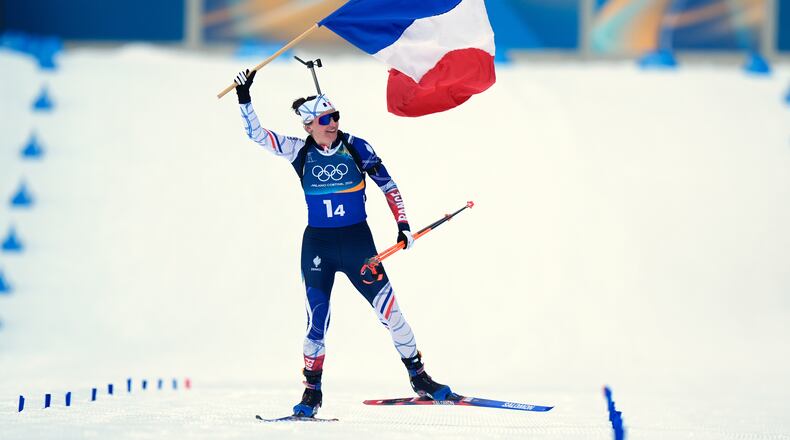 Julia Simon, of France, skis to the finish line with her country's flag for gold in the women's 4x6-kilometer relay biathlon race at the 2026 Winter Olympics in Anterselva, Italy, Wednesday, Feb. 18, 2026. (AP Photo/Andrew Medichini)