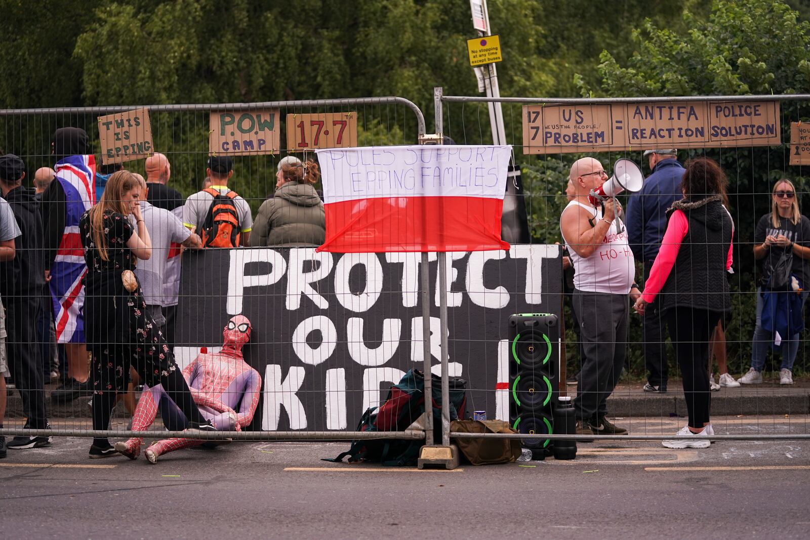 Demonstrators hold flags and placards as they stand outside the Bell Hotel in Epping, near London, Sunday, July 27, 2025.(AP Photo/Alberto Pezzali)