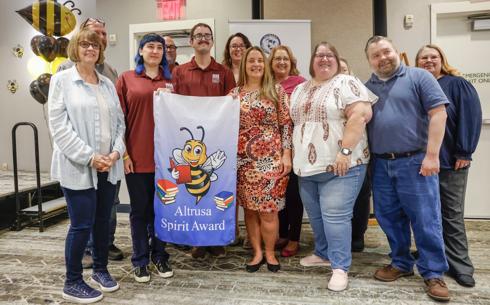 Miri Reyes, center far left, and Taylor Smith, center left, of "Bee A Leader," take a picture with a group to celebrate winning Altrusa's 26th annual Literacy Sting on Tuesday, September 23, 2025, at Springfield Courtyard by Marriott. JOSEPH COOKE/STAFF