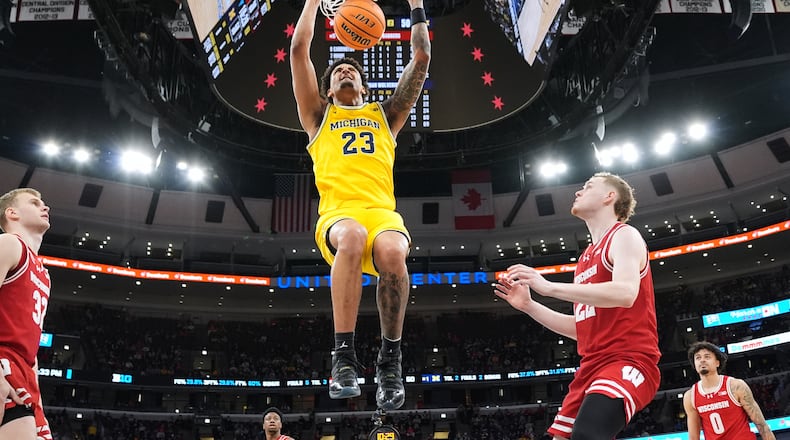 Michigan forward Yaxel Lendeborg hangs from the rim after dunking during the second half of an NCAA college basketball game against Wisconsin in the semifinals of the Big 10 Conference tournament, Saturday, March 14, 2026, in Chicago. (AP Photo/Nam Y. Huh)