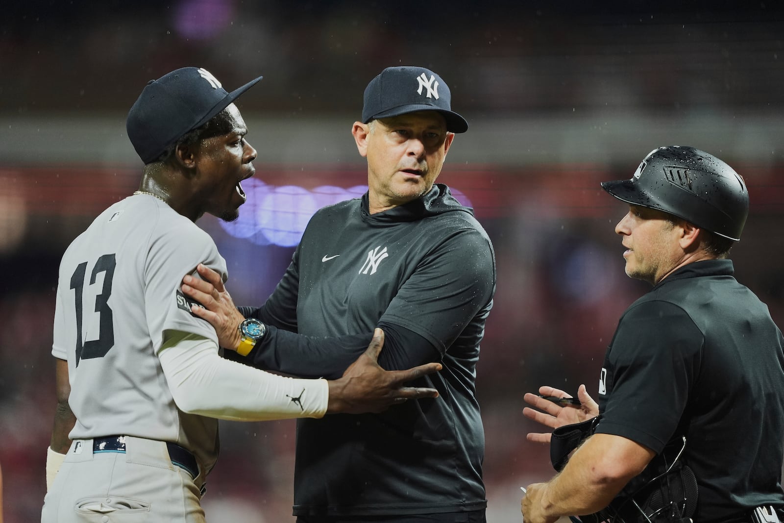 New York Yankees' manager Aaron Boone, center, stands between Jazz Chisholm Jr., left, and home plate umpire Mark Wegner, right, as Chisholm confronts Wegner after being called out on strikes during the ninth inning of a baseball game against the Cincinnati Reds, Tuesday, June 24, 2025, in Cincinnati. (AP Photo/Joshua A. Bickel)