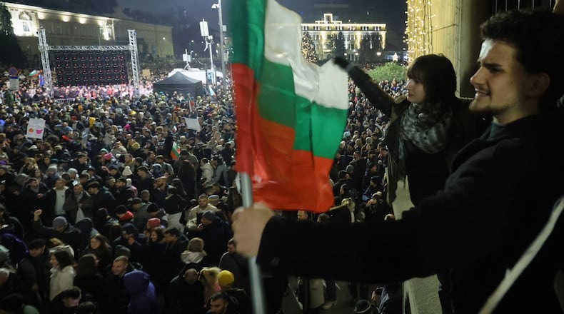 Students wave Bulgarian flag as as a swelling crowd of tens of thousands of Bulgarians filled Sofia's central square, demanding the government's resignation amid rising anger over corruption and contested economic policies, Sofia, Bulgaria, Wednesday, Dec. 10, 2025. (AP Photo/Valentina Petrova)