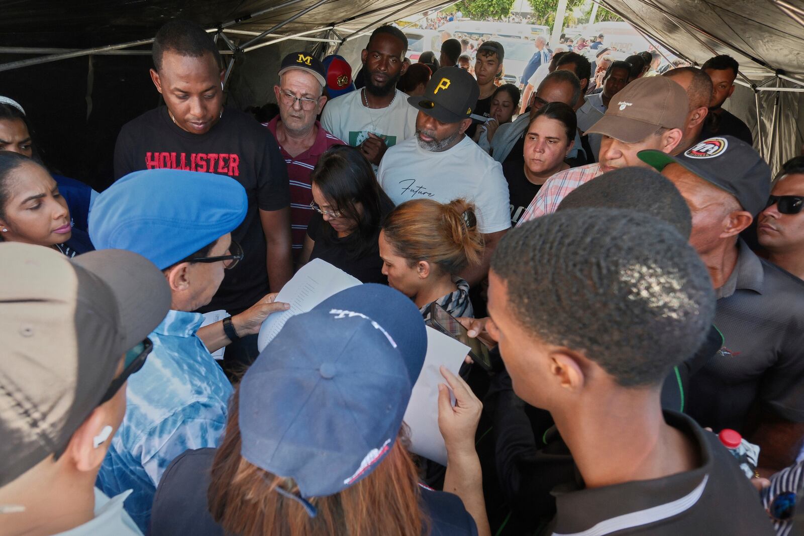 People listen to lists of survivors as crews search for others trapped in the Jet Set nightclub after its roof collapsed during a merengue concert in Santo Domingo, Dominican Republic, Tuesday, April 8, 2025.(AP Photo/Ricardo Hernandez)