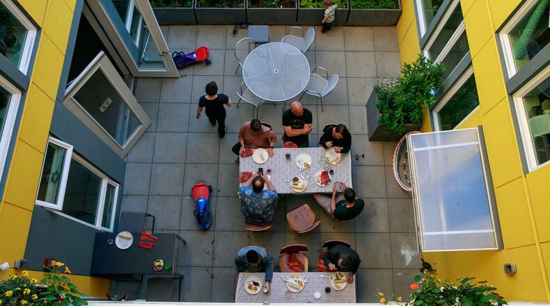 Residents of Capitol Hill Urban Cohousing talk over dinner in the central courtyard. We designed the building so all homes face the courtyard, says architect Grace Kim, who lives here with her family. When we were studying cohousing in Denmark, in general, Danish courtyards are in the center, so you d have shared outdoor space. Often the inside is a yellow/warm color. In the Pacific Northwest, it s really gray. Our concern was for light; it s nice to reflect happy yellow. Yellow goes through the common spaces. (Erika Schultz/The Seattle Times/TNS)