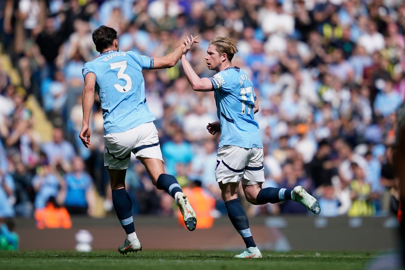 Manchester City's Kevin De Bruyne, right, celebrates with Ruben Dias scoring his side's first goal during the English Premier League soccer match between Manchester City and Crystal Palace at the Etihad stadium in Manchester, England, Saturday, April 12, 2025. (AP Photo/Dave Thompson)