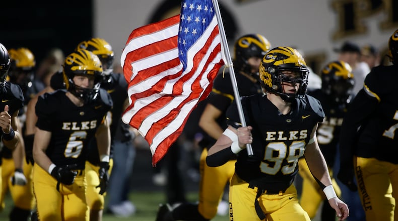 Centerville's Matthew Jones carries the flag onto the field before a Division I, Region 2 playoff game against Springfield on Friday, Nov. 3, 2023, at Centerville. David Jablonski/Staff