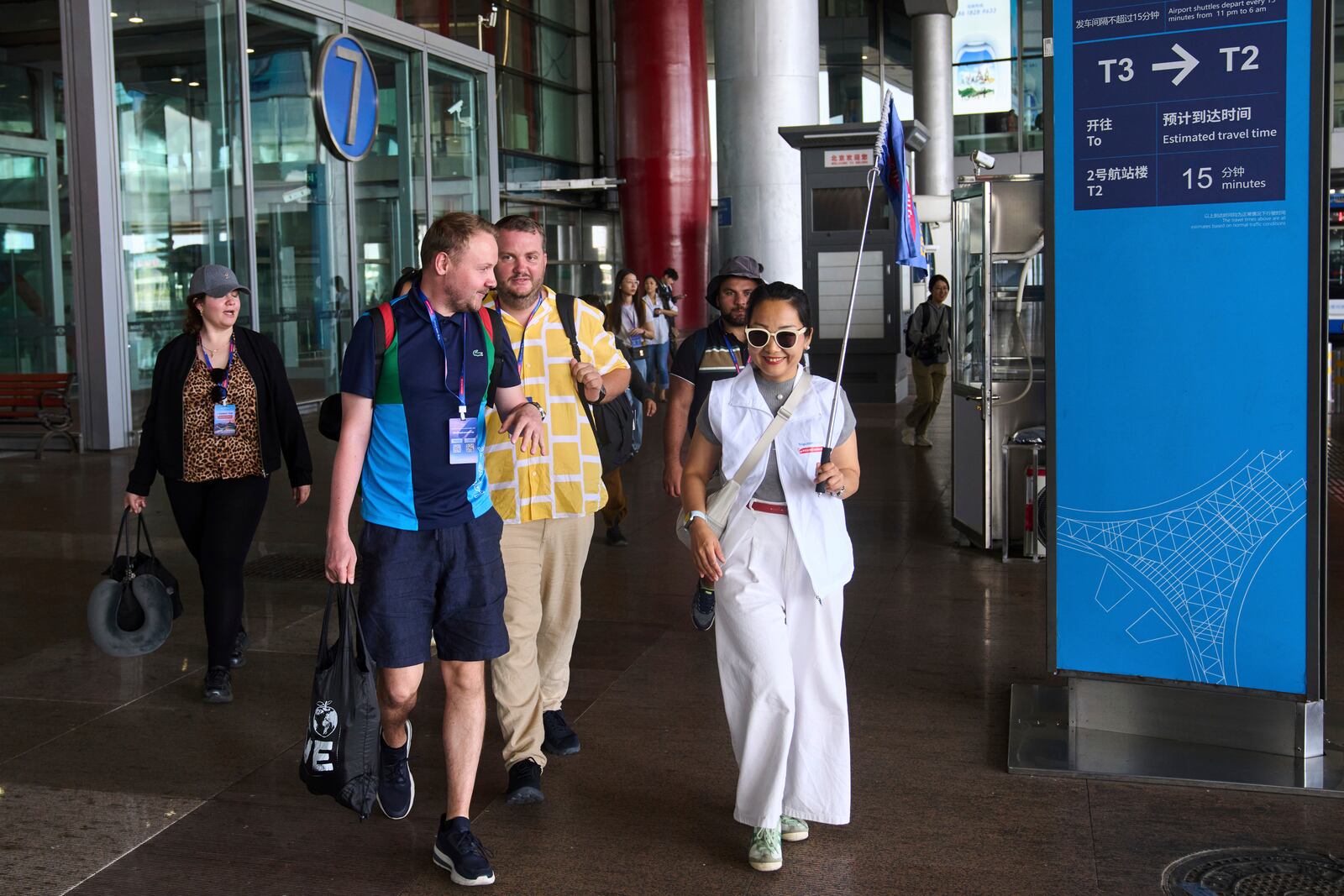 A tour guide leads tourists to the shutter bus to take a half-day tour to the tourism destination which offered by a travel agency Trip.com Group, at the Beijing Capital International Airport, in Beijing on June 15, 2025. (AP Photo/Andy Wong)