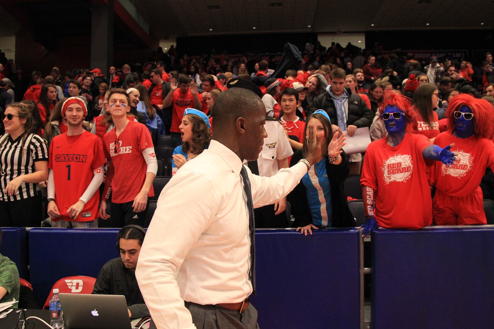 Dayton's Anthony Grant slaps hands with fans in the Red Scare section. Among the students is Sam Enderby, second from left.