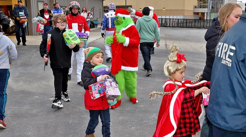 As the Grinch watches closely, Dayton Raceway horsemen and their children and grandchildren carry some of the many Christmas presents they donated to the annual Christmas from the Firehouse drive put on by Dayton Firefighters Union Local 136.  The presents were loaded onto a waiting firetruck at the track eight days ago and were given out to local families and children in need on Christmas Eve.  (Brad Conrad/ Conrad Photos)