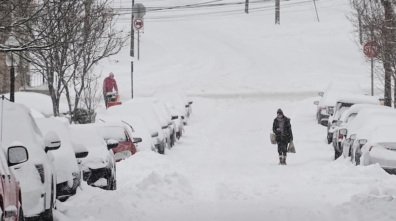 A person carries grocery bags up a residential street during a winter storm Sunday, Jan. 25, 2026, in Cincinnati. (AP Photo/Joshua A. Bickel)