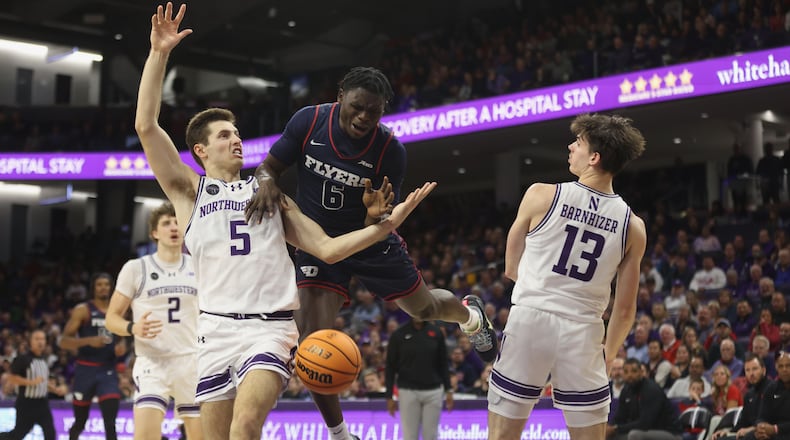 Dayton's Enoch Cheeks loses the ball as he drives to the basket against Northwestern's Ryan Langborg (5) and Brooks Barnhizer (13) on Friday, Nov. 10, 2023, at Welsh-Ryan Arena in Evanston, Ill. David Jablonski/Staff