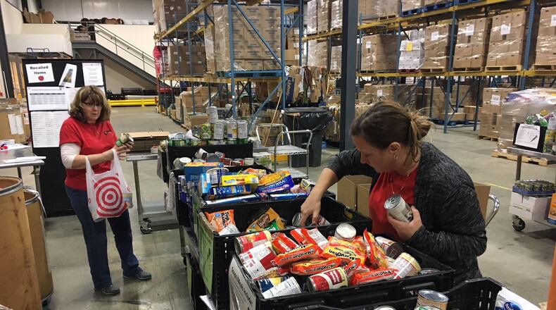 Malynda Norman and Amy Bork volunteer at The Foodbank in Dayton on Dec. 19. WILL GARBE / STAFF